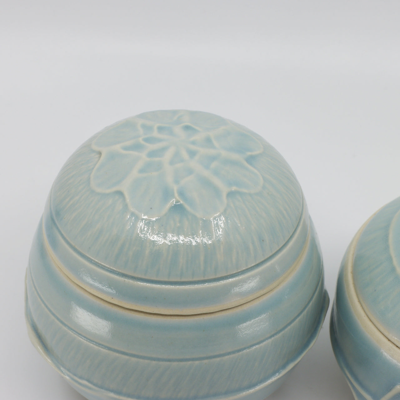 Détail d'un pot à couvercle bleu-vert, tourné et décoré à la main par la céramiste Chantal Parisien.